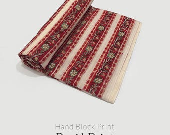 May include: Rolled and folded fabric with a cream background and vertical stripes in red and floral patterns. The text "Hand Block Print", "Rapid Print", and "Pure Cotton Fabric" is visible.