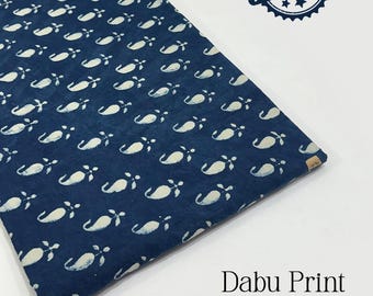 Pode incluir: Um pedaço de tecido azul marinho dobrado com um padrão paisley branco repetido. O tecido tem um carimbo que diz "100% Cotton". O texto "Dabu Print" e "Pure Cotton Fabric" também são visíveis.