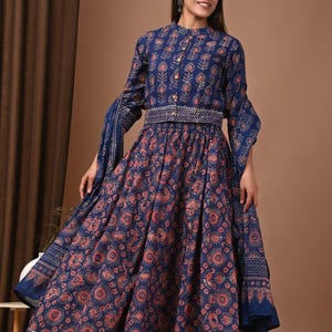 Puede incluir: Conjunto de dos piezas azul marino con estampado floral en tonos naranja y dorado. La parte superior tiene mangas largas y botones. La falda es amplia y fluida. Adecuado para ocasiones especiales.