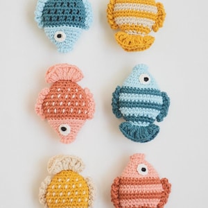 May include: Six crocheted fish toys in various colours and patterns. The fish are all about 10 cm long and have a simple, whimsical design.