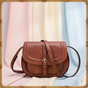 May include: A brown leather crossbody bag with a flap closure and adjustable strap. The bag features a buckle detail and a curved design. The background has a pastel colour scheme.