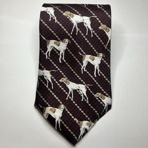 May include: A maroon necktie with a repeating pattern of white and brown dogs. The dogs are in a standing pose, and the background has a diagonal striped design. The tie is made of a smooth fabric.