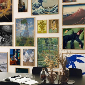 May include: A collection of framed art prints, including famous paintings like "The Great Wave off Kanagawa" and "Starry Night." The prints are displayed on a white wall above a black table with decorative vases and an open book.