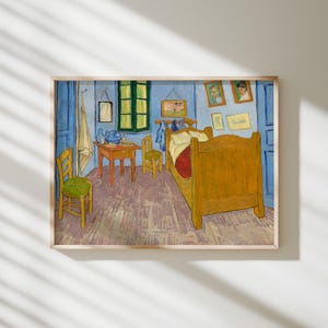 May include: Framed print of Vincent van Gogh's "Bedroom in Arles." The artwork depicts a bedroom with a wooden bed, chairs, and a table. The walls are painted blue, and the room is filled with furniture and artwork. The print is in a wooden frame.