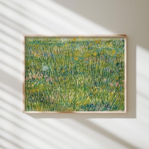Puede incluir: Una impresión enmarcada de un campo de hierba alta y verde con flores silvestres amarillas, rosas y azules. La obra de arte tiene un estilo impresionista texturizado. El marco es de color madera clara y la impresión se muestra en una pared blanca.