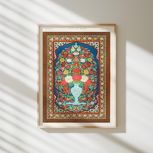 Op de afbeelding: Een ingelijste botanische kunstdruk getiteld Indian No. 6 met een centraal blauw paneel met een witte vaas gevuld met rode, witte en gele bloemen. Het kunstwerk is omgeven door een decoratieve bruine rand met ingewikkelde patronen en motieven.