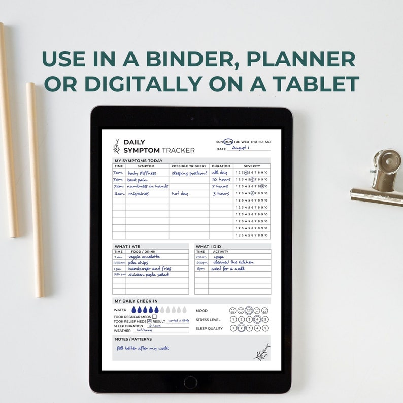 Op de afbeelding: Een zwarte tablet met een dagelijkse symptoomtracker-sjabloon met secties voor symptomen, voeding, activiteiten, waterinname, stemming en stress. De tekst luidt: USE IN A BINDER, PLANNER OR DIGITALLY ON A TABLET. Het formulier bevat handgeschreven notities.