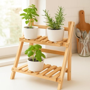 Puede incluir: Un estante de bambú de dos niveles con tres hierbas en macetas. Las hierbas son albahaca y romero, con hojas de color verde brillante. Las macetas de cerámica blanca contrastan con la madera de color marrón claro.
