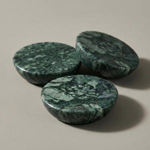 Può includere: Tre oggetti circolari realizzati in marmo verde levigato con venature scure naturali e una superficie liscia e arrotondata. Ogni pezzo presenta un motivo distinto di vortici verde bosco intenso e smeraldo più chiaro.
