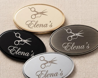 May include: Four oval-shaped name tags in gold, black, silver, and bronze. Each tag features a scissors graphic and the name "Elena's" in a cursive font. The tags are likely for a hair salon or beauty business.