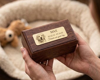 May include: A rectangular dark brown wooden box featuring a gold-toned metal plaque on the lid. The plaque is engraved with a portrait of a dog, the name MAX, the dates 03.12.12 - 07.14.23, and the text Forever our good boy.