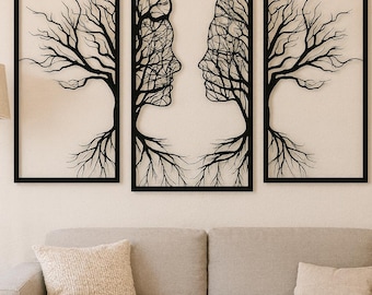 May include: Three-piece wall art set featuring black silhouettes of trees and faces. The central piece depicts two faces merging with tree branches, flanked by tree silhouettes. The artwork is framed in black and hangs above a gray sofa.