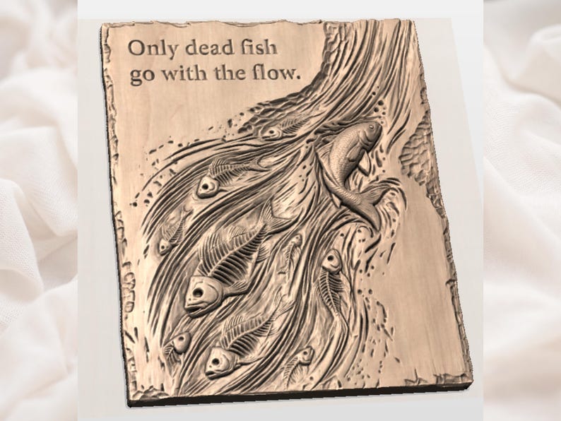 May include: A rectangular wooden plaque with the phrase "Only dead fish go with the flow" carved into the surface. The plaque features a relief carving of fish skeletons and a live fish swimming against the current. The colour is a warm, natural brown.