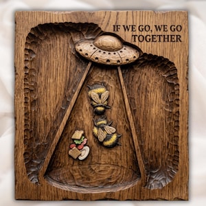 Könnte beinhalten: Dunkelbraune Holzplakette mit geschnitztem Design. Mit einem UFO, zwei Bienen und einem Sandwich. Der Text "IF WE GO, WE GO TOGETHER" ist oben eingraviert. Das Holz hat eine strukturierte Oberfläche.