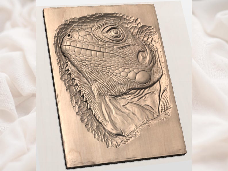 May include: A detailed wood carving of an iguana's head. The carving is in a rectangular shape and features intricate textures and scales. The iguana's eye, snout, and neck are prominently displayed, showcasing the craftsmanship. The wood has a natural, light brown color.