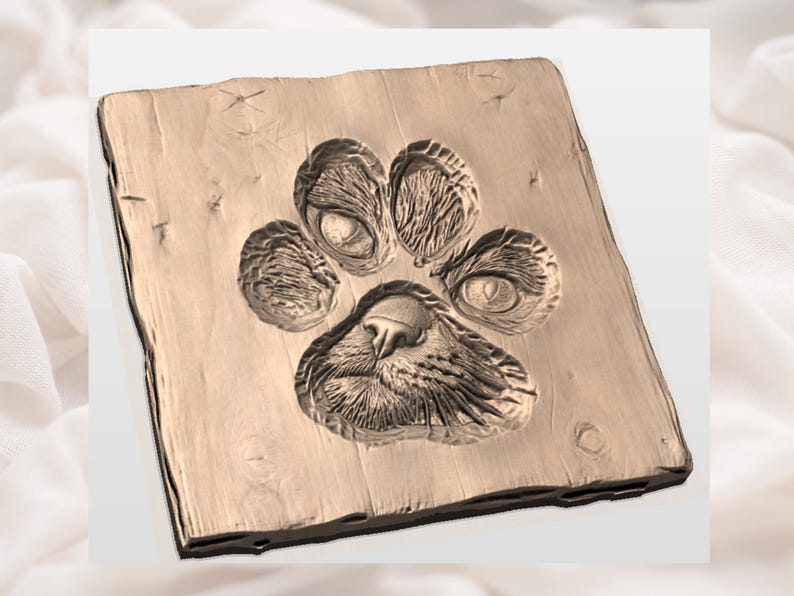May include: A wooden square with a detailed paw print carved into its surface. The paw print features textured pads and claw marks, creating a three-dimensional effect. The wood has a natural grain and a warm, light brown colour.