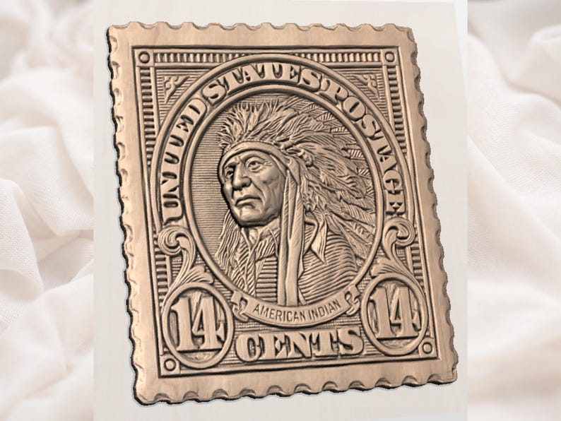 Puede incluir: Un relieve de color bronce de un sello postal vintage. El sello presenta un retrato de un jefe nativo americano dentro de un marco circular, con el texto "UNITED STATES POSTAGE" y "AMERICAN INDIAN 14 CENTS". El sello tiene un borde festoneado.
