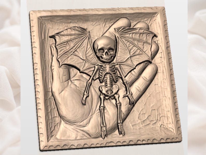 May include: A detailed relief carving of a skeletal figure with bat wings, set within a rectangular frame. The figure is posed in front of a hand, with intricate details on the wings and skeletal structure. The color is a light brown.