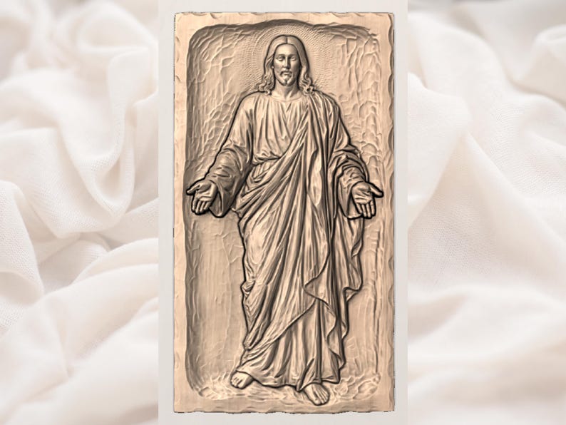 May include: A bronze-coloured relief sculpture of a figure with long hair and a beard, wearing draped robes, with arms outstretched. The sculpture is set within a rectangular frame, against a soft, off-white fabric background.