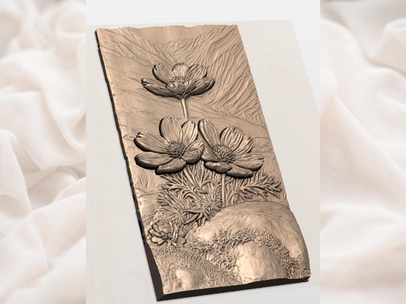 Op de afbeelding: Een bronzen reli&euml;fsculptuur met drie gedetailleerde bloemen met meerdere bloemblaadjes. De bloemen staan tegen een achtergrond met textuur met een bergachtig ontwerp en een rotsformatie aan de basis. De sculptuur is op een donker frame gemonteerd.