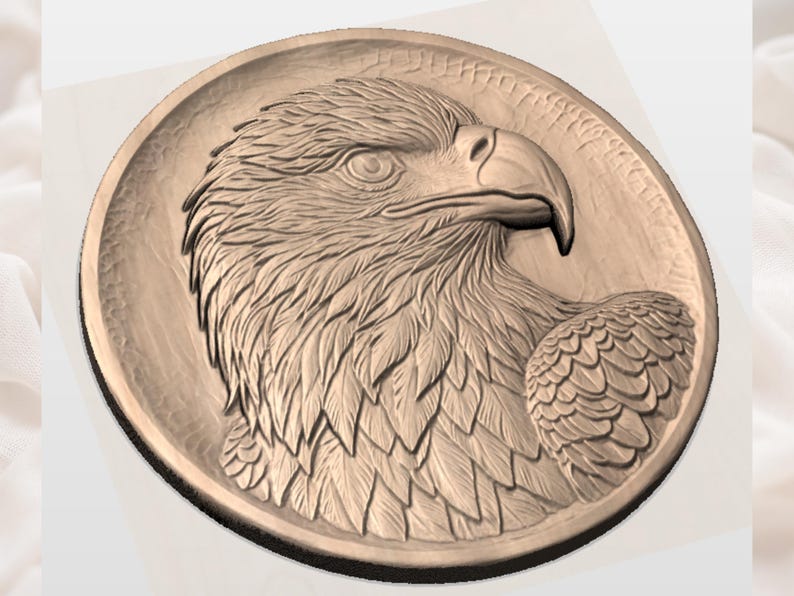 May include: A bronze-colored, circular relief sculpture featuring a detailed profile of an eagle's head. The eagle's eye, beak, and feathers are intricately carved, showcasing a sense of depth and texture. The artwork is set against a smooth, circular background.