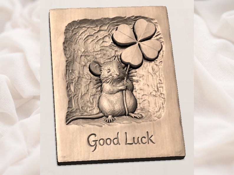 May include: A wooden plaque with a carved relief of a mouse holding a four-leaf clover. The words "Good Luck" are carved below the mouse. The plaque has a light brown color and a textured background.