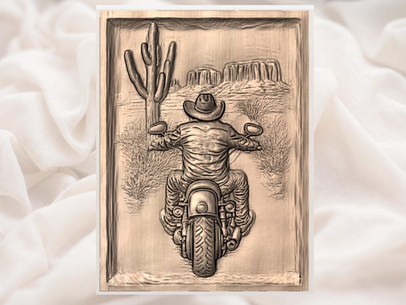 May include: A wooden relief carving shows a cowboy on a motorcycle in a desert scene. A large cactus and distant mesas are visible. The carving is framed and has a natural wood tone.