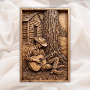 May include: Wooden relief carving of a cowboy playing a guitar, leaning against a tree. The artwork depicts a cabin, a tree, and a grassy area. The cowboy wears a hat, shirt, and boots. The carving is framed in wood.
