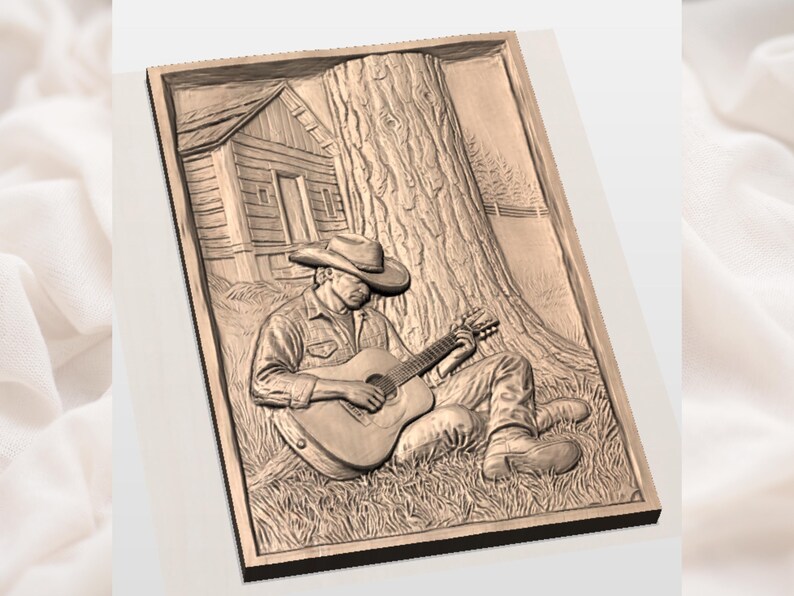 May include: A detailed relief carving shows a person playing a guitar under a tree, with a small cabin in the background. The artwork is framed and features a cowboy hat and boots. The carving is in shades of brown and tan.