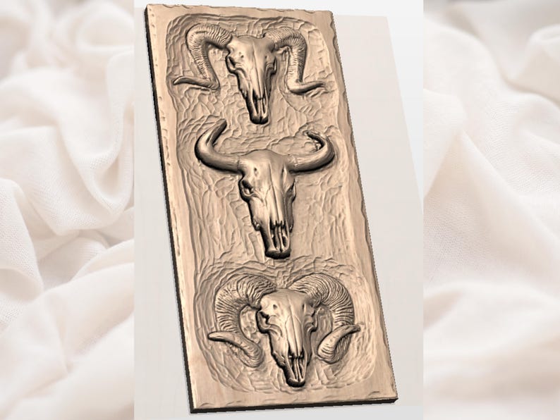 Op de afbeelding: Een rechthoekig, bronskleurig reli&euml;fbeeld met drie dierenschedels. De bovenste en onderste schedels hebben gebogen hoorns, terwijl de middelste schedel rechte hoorns heeft. De achtergrond heeft een getextureerd, gebeeldhouwd uiterlijk.