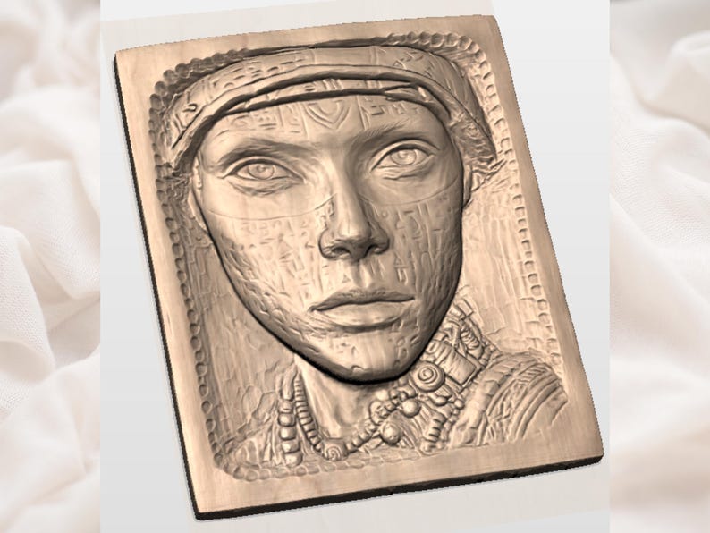 May include: A wooden relief carving of a woman's face, featuring detailed facial features and adorned with a head covering and necklace. The carving is set within a rectangular frame with a decorative border, showcasing intricate textures and patterns.