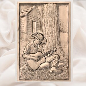 May include: A sepia-toned relief carving shows a person in a cowboy hat playing a guitar, seated against a large tree. A small cabin is visible in the background. The artwork is framed and set against a soft, white background.