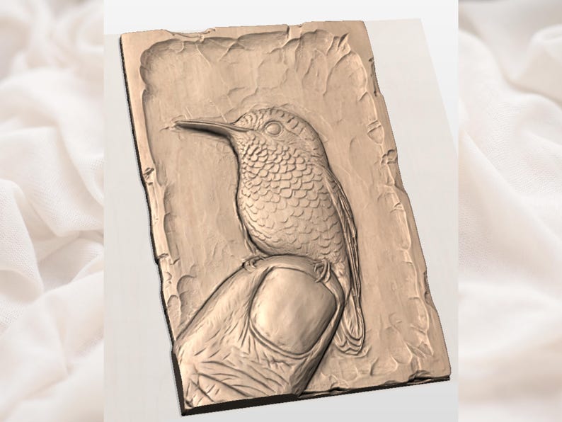 May include: A detailed relief carving of a hummingbird perched on a finger. The artwork is rendered in a warm, earthy tone, showcasing the bird's intricate feather details and the textured surface of the background. The carving is rectangular with a rough, natural edge.
