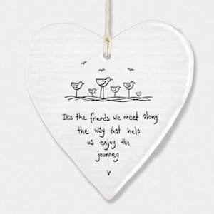 May include: White heart-shaped plaque with a string for hanging. The plaque has a black line drawing of birds and the text: "It's the friends we meet along the way that help us enjoy the journey."