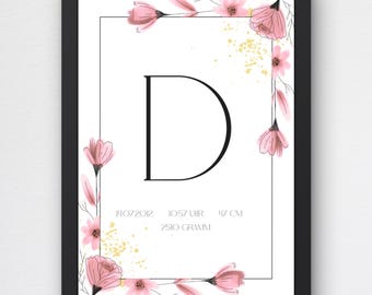 May include: A framed birth poster featuring a large black letter D centred within a rectangular border. The design includes pink floral illustrations and gold speckles. Text includes 14.07.2012, 10:57 UHR, 47 CM, and 2510 GRAMM. The frame is black.