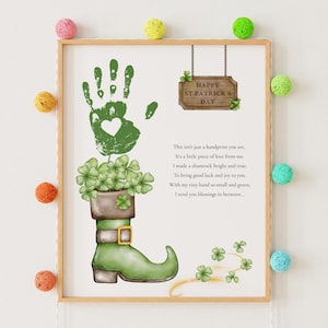 Puede incluir: Una impresión enmarcada del Día de San Patricio con una huella de mano verde con un corazón, una bota verde con tréboles y un letrero de madera que dice "Happy St. Patrick's Day". La impresión incluye un poema.