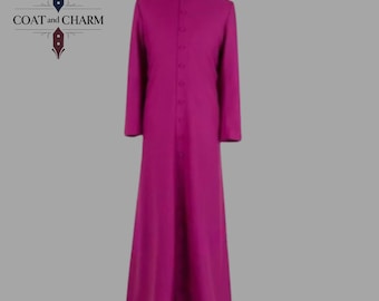 Può includere: Una lunga veste color magenta con colletto alla coreana e maniche lunghe. La veste è abbottonata sul davanti ed è esposta su un manichino. Il testo "COAT and CHARM" si trova nell'angolo in alto a sinistra.