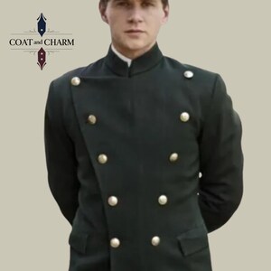 May include: A dark green coat with a high collar and gold buttons. The coat has a double-breasted design and two pockets. The text "COAT and CHARM" is visible in the upper left corner. The coat is worn by a person.