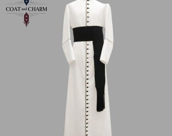 May include: A white, long-sleeved coat with a mandarin collar and a black sash. The coat features a row of small buttons down the front and on the sleeves. The text "COAT and CHARM" is in the upper left corner.