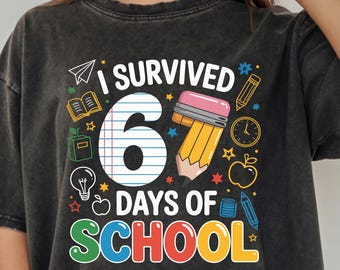 May include: Dark gray t-shirt with the text "I Survived 6 Days of School" in colorful letters. The graphic includes a pencil, apple, and other school-related icons. The shirt is a relaxed fit.