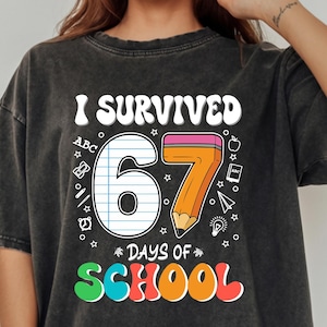 Peut inclure: T-shirt gris foncé avec l'inscription "I Survived 67 Days of School" dans une police rétro colorée. Le motif comprend le chiffre 67, un crayon et des graphiques scolaires. Le t-shirt est de coupe ample et décontractée.