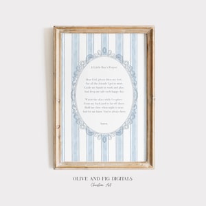 May include: A framed print with a prayer for a young boy, set against a blue and white striped backdrop. The prayer is enclosed in an oval frame with decorative elements. The frame is a light brown colour. The text at the bottom reads "Olive and Fig Digitals Christian Art."