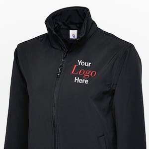 May include: Black jacket with a full-length zip, a stand-up collar, and two side pockets. The text "Your Logo Here" is embroidered in red on the upper left chest area. The jacket is made of a smooth, matte material.