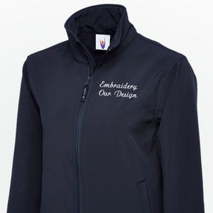 Puede incluir: Chaqueta azul marino con cremallera completa y cuello alzado. Cuenta con dos bolsillos laterales y el texto bordado "Embroidery Our Design" en blanco. Una prenda de abrigo versátil y funcional.