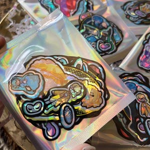 Può includere: Una collezione di adesivi colorati in confezione olografica. Gli adesivi presentano illustrazioni di cartoni animati con contorni neri e vari colori. Gli adesivi sono in sacchetti trasparenti e sigillati.