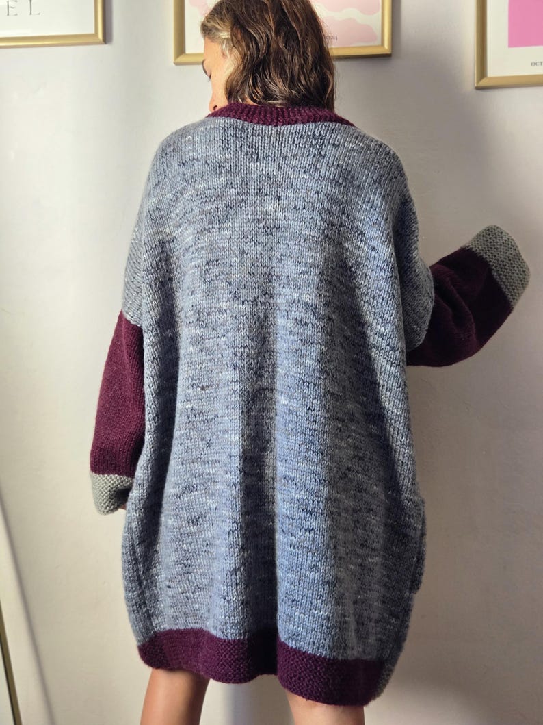 Puede incluir: Un c&aacute;rdigan de punto gris extragrande con mangas y ribetes burdeos. El c&aacute;rdigan tiene un aspecto texturizado y presenta un cuello y dobladillo burdeos oscuro. Las mangas tienen pu&ntilde;os grises. La prenda parece hecha a mano.