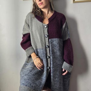 Puede incluir: Un c&aacute;rdigan largo con botones en tonos grises y burdeos. El su&eacute;ter de gran tama&ntilde;o presenta un dise&ntilde;o de bloques de color con cuello en V y bolsillos grandes. Las mangas y el dobladillo tienen pu&ntilde;os acanalados. El c&aacute;rdigan est&aacute; hecho de punto grueso y texturizado.