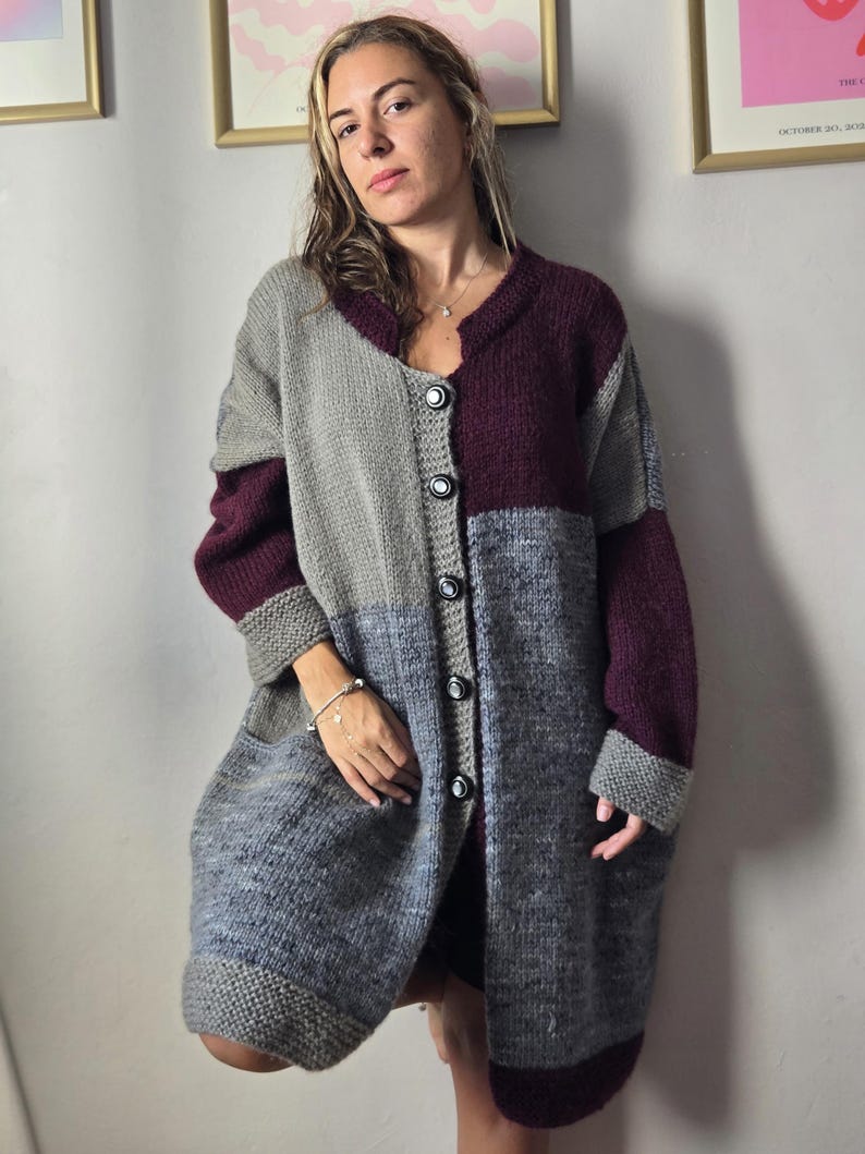 Puede incluir: Un c&aacute;rdigan largo con botones en tonos grises y burdeos. El su&eacute;ter de gran tama&ntilde;o presenta un dise&ntilde;o de bloques de color con cuello en V y bolsillos grandes. Las mangas y el dobladillo tienen pu&ntilde;os acanalados. El c&aacute;rdigan est&aacute; hecho de punto grueso y texturizado.