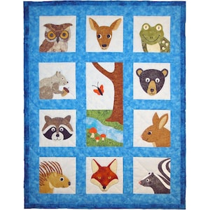 Peut inclure: Une courtepointe rectangulaire avec une bordure bleue et une grille de carrés blancs. Chaque carré présente une applique en tissu d'un animal des bois, notamment un hibou, un cerf, une grenouille, un écureuil, un ours, un raton laveur, un lapin, un porc-épic, un renard et une mouffette.
