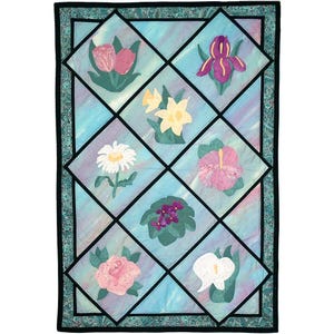 May include: A rectangular fabric quilt featuring a diamond-patterned grid. Each diamond contains a different embroidered flower, including a tulip, iris, daffodil, daisy, hibiscus, violet, rose, and calla lily, set against a light blue background.